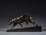 une photo d'une sculpture en bronze représentant un tigre sur un socle noir