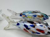 three glass fish figurines sitting on a white surface