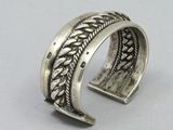 a close up of a silver bracelet with a braid design on it