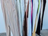 de nombreux pantalons suspendus à un portant devant un mur blanc