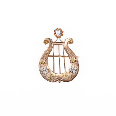 une image représentant une broche en forme de harpe en or et diamants