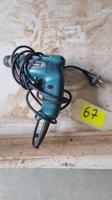 une perceuse filaire posée sur un morceau de bois