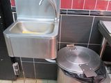 a sink and a trash can in a public restroom