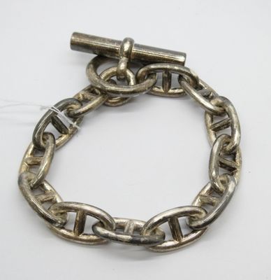 une image représentant un bracelet en argent muni d'un fermoir, posé sur une surface blanche