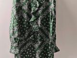 une photo d'une veste à motifs cachemire verts et blancs, suspendue à un cintre