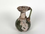 une image représentant un vase vert et blanc posé sur une surface blanche
