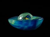 a glass bowl with a marble in it on a black background