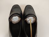 pair of black leather shoes with a wooden stick sticking out of them
