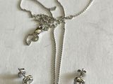 un ensemble composé d'un collier et de boucles d'oreilles en argent, posé sur une surface blanche