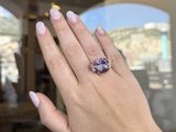 someone is holding up a ring with a purple stone on it
