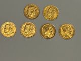 six souverains d'or alignés sur une surface blanche