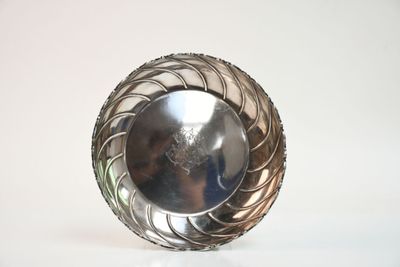 un bol en argent posé sur une surface blanche