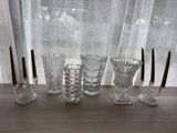 five glasses and a candle holder sitting on a table