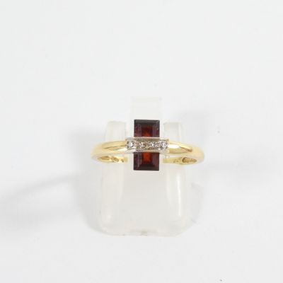 a close up of a gold ring with a red stone and a diamond