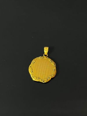 a gold plated pendant with a circular design on a black background