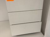 a white chest of drawers with a yellow label on it