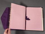 a person holding a purple book with a bird on it