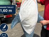 a man standing next to a large shark that is being held by a truck
