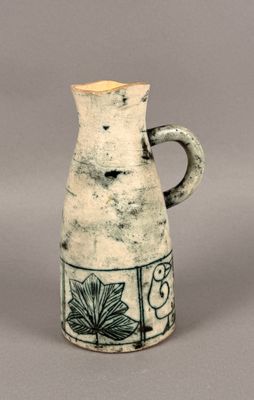 a white and black vase with a flower design on it