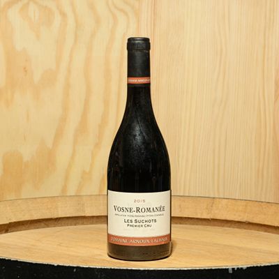 a bottle of wine sitting on top of a barrel