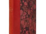 un vieux livre à la couverture rouge posé sur une surface blanche