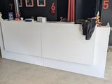 un comptoir d'accueil blanc dans une pièce où sont accrochés des tableaux aux murs