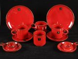 un ensemble d'assiettes et de tasses rouges posées sur une table noire