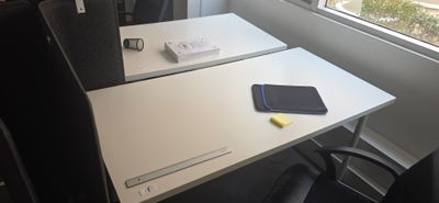 un bureau blanc avec une chaise noire près d'une fenêtre