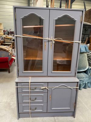 a gray cabinet with glass doors and a rope on the top