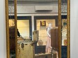 un miroir accroché au mur dans lequel se reflète une femme en robe rose