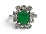 gros plan d'une bague avec une pierre verte entourée de diamants blancs