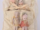 three dolls sitting in a bag on a white surface