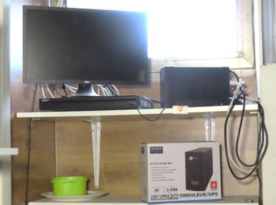 a shelf with a monitor, speakers, and other electronics on it