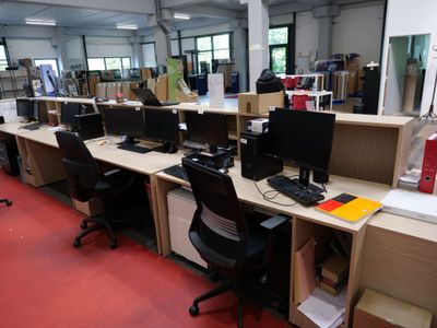 des rangées de bureaux équipés d'ordinateurs et de chaises dans un grand espace ouvert