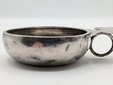 un bol en argent avec une poignée sur une surface blanche