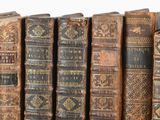 many old books lined up on a shelf in a row