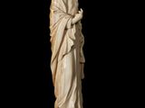a statue of a man in a robe standing on a black surface
