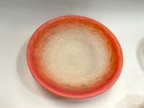 a red and white bowl sitting on a table next to a white plate