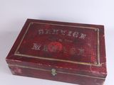 an old wooden box with writing on it sitting on a white surface