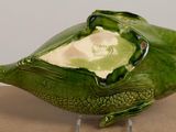 a green bird shaped bowl on a stand on a table