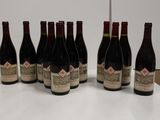 six bottles of red wine are lined up on a table