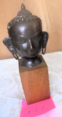 a small statue of a buddha head on a wooden block