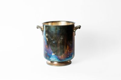 un gros plan d'une tasse en métal posée sur une surface blanche