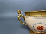 a white and gold cup with a gold handle on a blue background