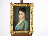 un tableau représentant une femme avec un nœud bleu, posé sur un chevalet