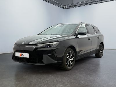Une voiture grise est garée dans une grande pièce aux murs blancs.