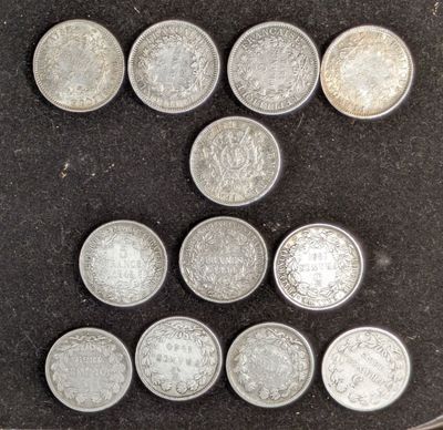 six types différents de pièces d'argent sont disposés sur une surface noire