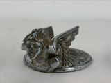 a silver statue of a winged animal on a white surface