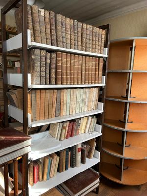 Les livres sont empilés sur une étagère dans une pièce où se trouvent de nombreux livres.