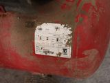 a red air compressor sitting on the ground with a sticker on it